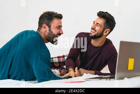Happy gay men couple using laptop in bed - Homosexual love and gender equality in relationship concept Stock Photo