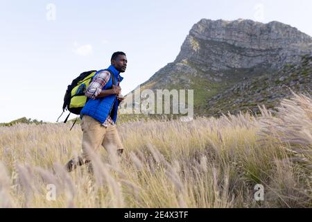 Fit afrcan american man wearing backpack hiking in mountain countryside Stock Photo