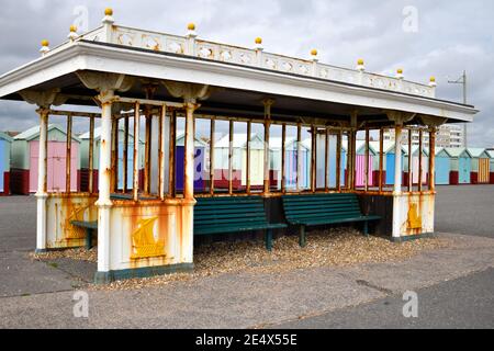 Rusty derelict seafront shelter with Brighton beach huts, Sussex, UK Stock Photo