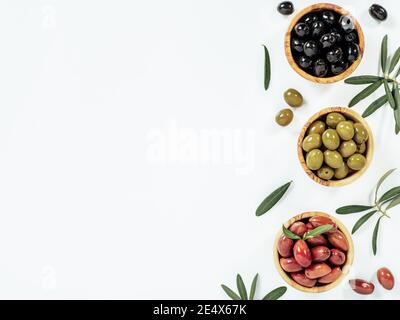 Set of green olives, black olives and red kalmata olives on white background,copy space. Top view of different olives types in bowls and leaves and branches isolated on white. Beautiful olive flat lay Stock Photo
