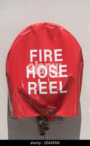 Fire Hose Reel covered by very bright shiny red cover with large white  lettering. Emergency water supply mounted on exterior white wall Stock  Photo - Alamy