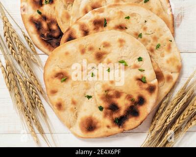 Fresh naan bread on white wooden background with copy space. Top view of several perfect naan flatbreads on metal tray Stock Photo