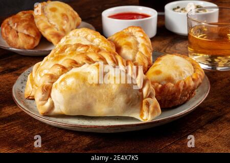 Empanadas with wine and various sauces on a dark rustic wooden background Stock Photo