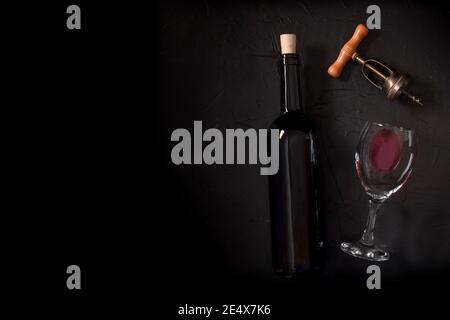 Wine tasting, top shot on a black background, with a cork, corkscrew, and a bottle, with copy space Stock Photo