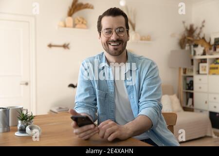 Portrait of laughing young man distracted from smartphone screen Stock Photo