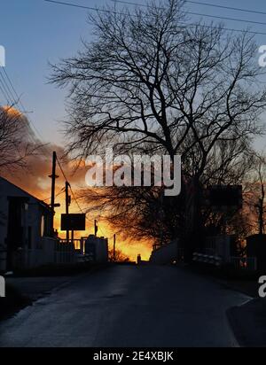 The firey sun is just going down up on a cool winters afternoon over the swing bridge that crosses the canal at Crabtree Lane near Burscough Stock Photo