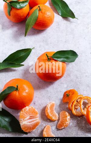 Fresh clementines with leaves on and fruit segments and peel to the side. Stock Photo