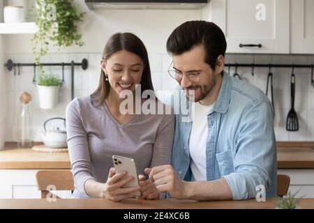Smiling wife demonstrating husband interesting photo on phone screen Stock Photo