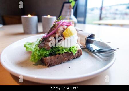 smorrebrod with herring, egg and lemon on dark bread close-up. horizontal Stock Photo