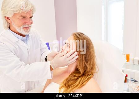 Dermatologist examines female patient before cosmetic surgery in doctor's office Stock Photo