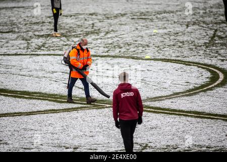 Ground staff at football stadium clear snow from pitch ahead of match. Stock Photo