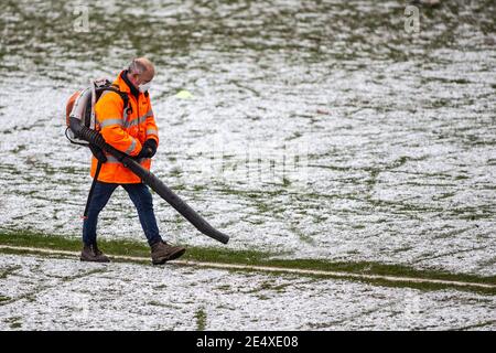 Ground staff at football stadium clear snow from pitch ahead of match. Stock Photo