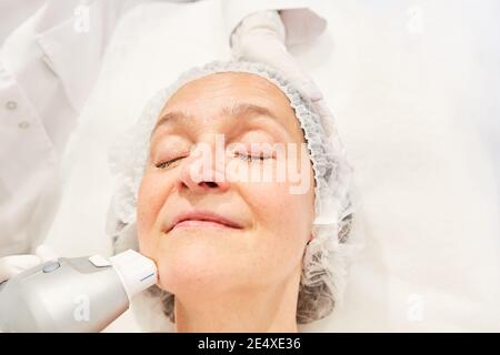 Elderly woman having an ultrasound treatment on her neck for wrinkles and skin tightening Stock Photo