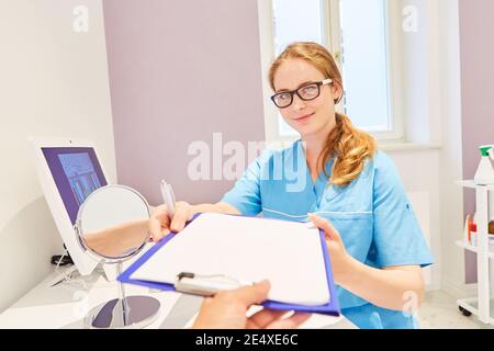A doctor receives a checklist or patient file from a colleague in her doctor's office Stock Photo