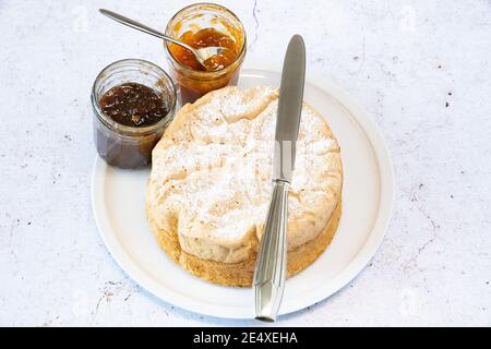 Homemade Savoie cake on a pretty white porcelain dish with jam in a jar Stock Photo