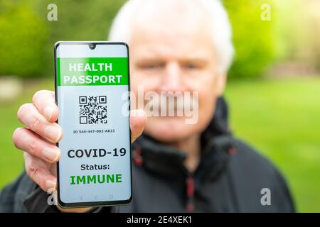 Senior man showing a health passport on a mobile phone, which indicates a vaccination against covid-19. Stock Photo