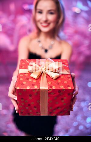 Pleased young woman holding a gift box with both hands Stock Photo