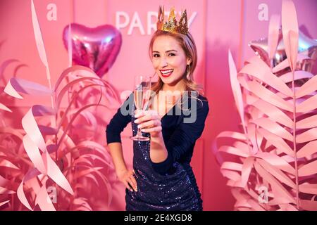 High-spirited lady with a glass of champagne looking ahead Stock Photo