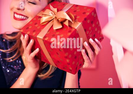 Happy lady pressing the gift box to her ear Stock Photo