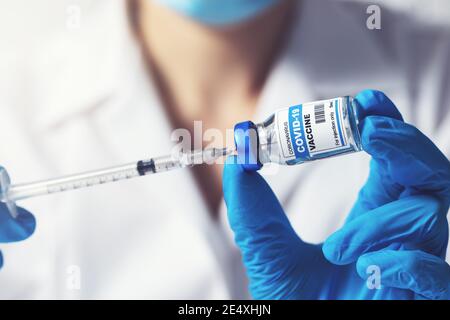 doctor preparing covid-19 vaccine dose for vaccination. closeup of syringe and vial in hands Stock Photo