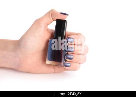 Hand of a woman with dark manicure and nail polish bottle on white background Stock Photo