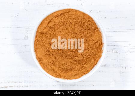 Cinnamon spice powder from above bowl wooden board wood Stock Photo