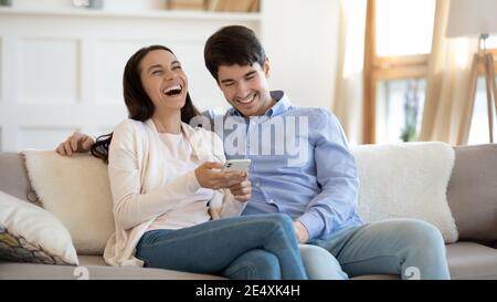 Happy young couple using phone, laughing, having fun together Stock Photo