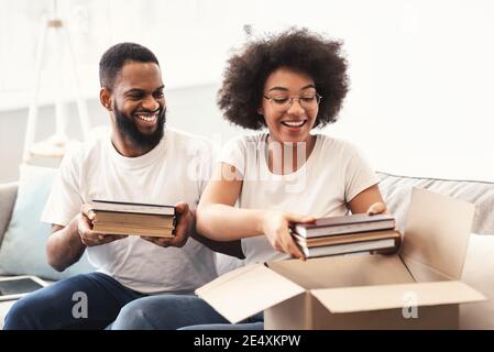 Joyful Black Couple Packing Moving Boxes Indoors Preparing For Relocation Stock Photo