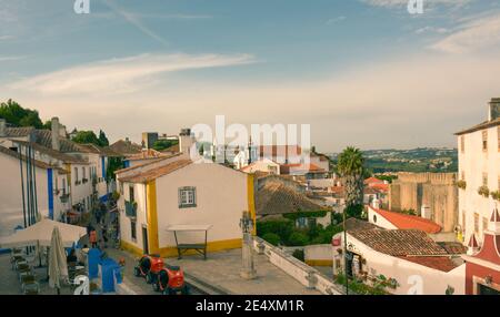 Obidos, Portugal - 16th May, 2017: Tourists exploring the narrow cobbled stone streets of the medieval town of Obidos in Portugal. Stock Photo