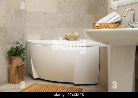 Bathtub, sink and wooden accessories in a beige bathroom, a calm bathroom interior, a modern bathroom with soft light Stock Photo