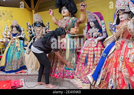 A devout Hindu woman prepares new clothing for the statues of deities in her termple. In Queens, New York City. Stock Photo