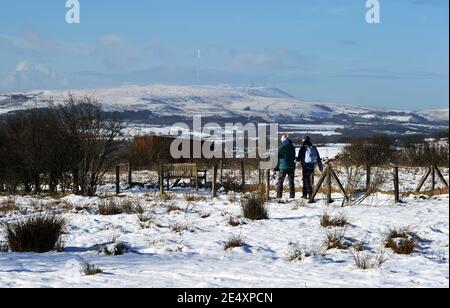 Bury, Greater Manchester, England, 25th January 2021. Walkers in the snow covered fields around the village of Affestide, Bury with the aptly named Winter Hill in the background. The North West of England woke up to a fresh blanket of snow to start the new week. Credit: Paul Heyes/ Alamy Live News Stock Photo