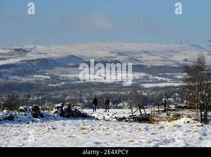 Bury, Greater Manchester, England, 25th January 2021. Walkers in the snow covered fields around the village of Affestide, Bury with the aptly named Winter Hill in the background. The North West of England woke up to a fresh blanket of snow to start the new week. Credit: Paul Heyes/ Alamy Live News Stock Photo