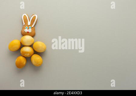 Abstract bunny made of yellow painted easter eggs and cookies on bright blue background, easter festive concept Stock Photo