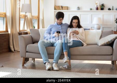Obsessed man and woman using phones, ignoring each other