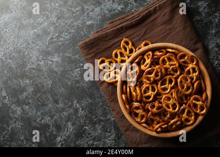 Wooden bowl with tasty cracker pretzels on napkin on black smokey background Stock Photo