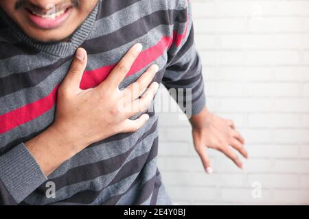 the concept of heart attack , man having pain in heart and holding chest with hand  Stock Photo