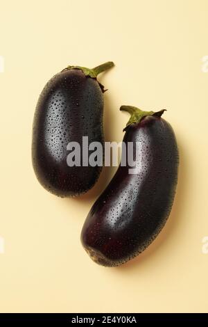 Fresh raw eggplants with water drops on beige  background Stock Photo