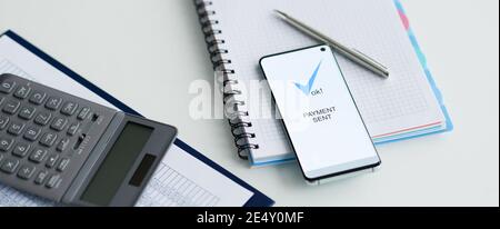 On table lies a smartphone with inscription payment sent documents and calculator Stock Photo