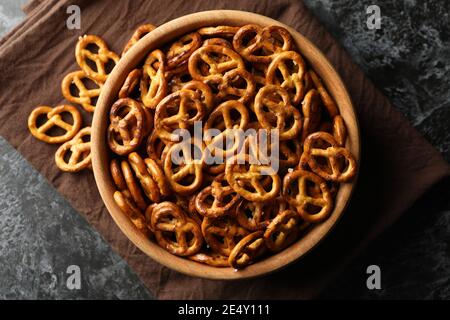 Wooden bowl with tasty cracker pretzels on napkin on black smokey background Stock Photo