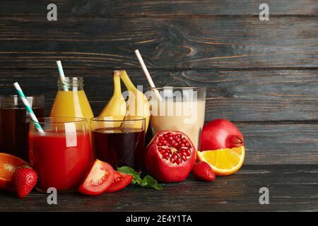 Glasses and jars with different fruit and vegetable juices on a wooden background, a colorful healthy drink selection Stock Photo