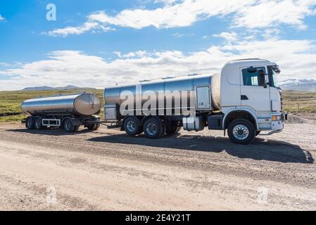 Milk truck with a trailer parked along an unpaved road in the countryside of Iceland on a sunny summer day Stock Photo