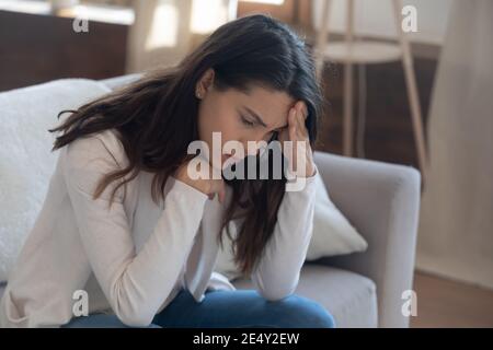 Unhappy young woman touching forehead, thinking about relationship problems Stock Photo