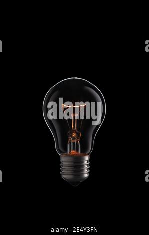 Burning Light bulb on black background. Stock Photo