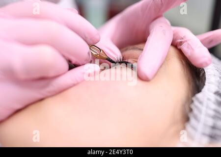 Master performs permanent makeup on eyelids by making decorative arrow Stock Photo