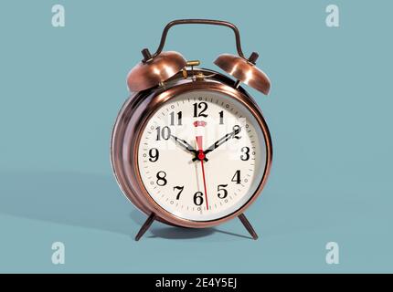 Classic bronze coloured vintage style alarm clock with bells and a modern dial with a red second hand on a blue background Stock Photo