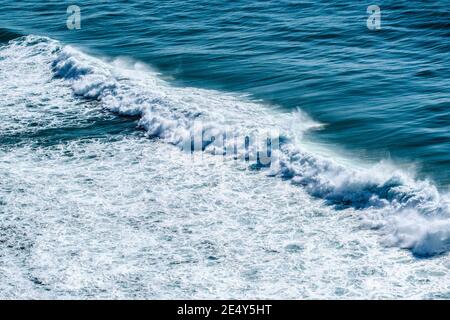 safire colored waves of the sea with its surf approaching the beach seen from above Stock Photo