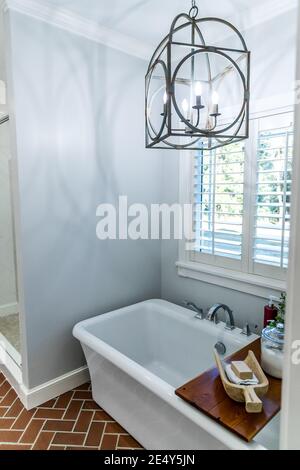 Large white renovated master bathroom bathtub with red brick floors Stock Photo