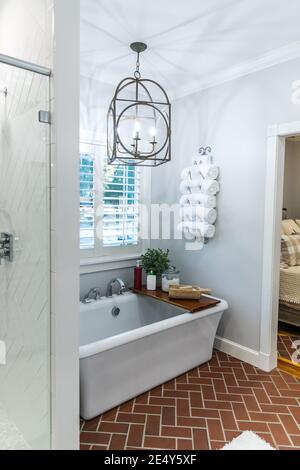 Large white renovated master bathroom bathtub with red brick floors Stock Photo