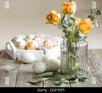A bouquet of flowers in a glass vase with decorative elements on a blurred background. Easter holiday concept. Stock Photo